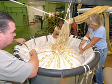 Workers pack parachute into container.