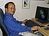 NASA scientist Lee-Lueng Fu smiles while sitting at his computer studying satellite images