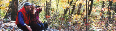 A father and son using binoculars in the fall forest.