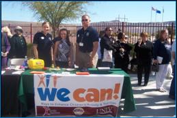 Image of people with Miss Nevada standing behind We Can event table