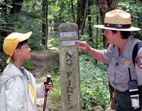 A ranger shows a young hiker how to read the information on a stone trailmarker during a Ranger Program.