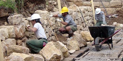 3 masons reconstructing historic wall.
