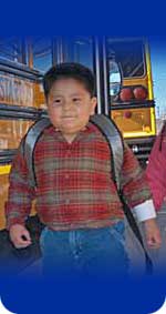 Photo of a boy walking by a school bus