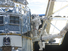 Two astronauts work on the Hubble during a a previous servicing mission in 2002