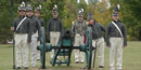 Park staff and volunteers demonstrating using lindstock and slowmatch to ignite the cannon's primer