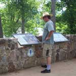 visitor looks at wayside panels on Trail of Tears at Trail of Tears Overlook along the Arkansas River