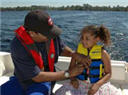 Father and daughter wearing life jackets aboard a boat.