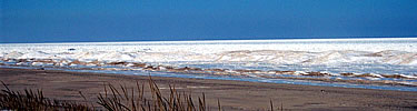 Snow covered ice along the bare sand of Lake Michigan