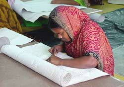 Photo of: A woman embosses leather that will be used to manufacture handbags and shoes for export.