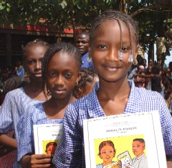 Guinean schoolgirls receive language arts textbooks donated by USAID.