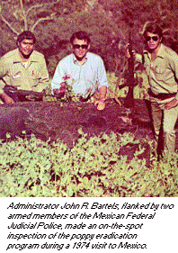 photo - Administrator John R. Bartels, flanked by two armed members of the Mexican Federal Judicial Police, made an on-the-spot inspection of the poppy eradication program during a 1974 visit to Mexico.