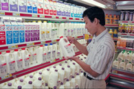 Image of a man browsing in a typical dairy case at a grocery store.