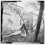 Portrait of a lone black woman in bonnet holding basket standing in front of the "slave pen" in Alexandria, Va. ...--see entry below