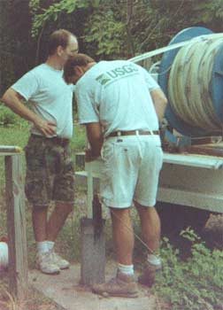  [Photo of scientists lowering pump into borehole]