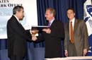Secretary Gutierrez hands document to Daimler Chrysler executive during ceremonial signing