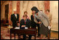 Mrs. Laura Bush, along with family of Ambassador Mark Dybul, watch as U.S. Secretary of State Condoleezza Rice assists newly sworn-in Ambassador Mark Dybul as he signs appointment documents Tuesday, October 10, 2006, during the swearing-in ceremony of Ambassador Mark Dybul in the Benjamin Franklin Room at the U.S. Department of State in Washington, D.C. White House photo by Shealah Craighead