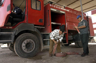photo: Fire fighters at newly renovated Kirkuk fire station load fire hoses and tools into fire truck.