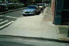 Case Study: Front and side photos showing the addition of a curb extension (bulbout into the parking lane) at an existing corner to provide sidewalk space for a ramp at the crossing.