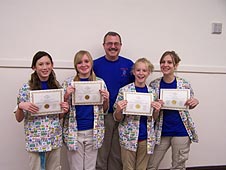Four girls stand with their teacher and hold their award certificates