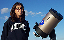 Photograph of Abigail standing next to a telescope