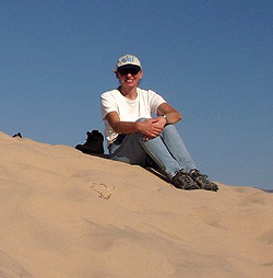 Picture of Diane Evans sitting on top of a sand dune