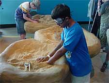 A 14-year-old blind boy named Steven is digging in a container of soil at the Maryland Science Center