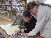 Alice Shaw, Diane Bowen and Ben Hauptman looking at a lithograph
