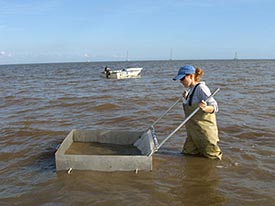 Lissa Lyncker stands in knee-deep water as her boat floats in the background