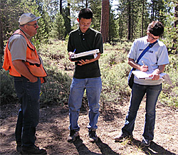Photograph of Michael Jin and Catherine Huybrechts taking notes while speaking with the U.S. Forest Service's Karl Greulich