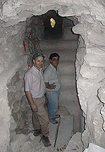 Two men standing in a cave-like opening