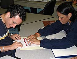 Wanda Diaz helps a student read a book that is written in Braille