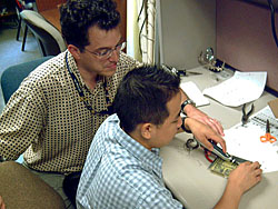 Leonard Garcia watches as Young Lee uses a soldering iron
