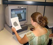 A student compares the graphic on a piece of paper to what is on her computer monitor