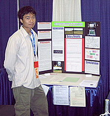 Hieu Tran stands next to a poster presentation