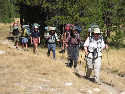 Several people hiking down a trail in single file