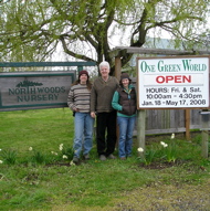 Nursery owners and sustainability director stand next to nursery signs.