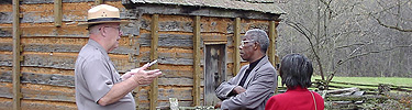 A picture of visitors talking with a park guide at the Boyhood Home Unit at Knob Creek