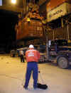 A member of the Coast Guard looking at containers through a camera mounted on a tripod.