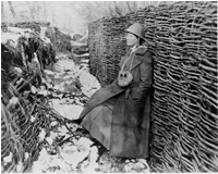 Helen Johns Kirtland in trench during World War I; she is wearing a helmet and great coat, and has a gas mask hanging around her neck