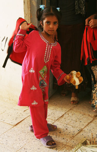 An Iraqi girl swings her new backpack over her shoulder, Aug. 21, 2008. Teachers passed out school supplies and toys to the students after receiving them from U.S. Marines.  Photo by Lance Cpl. Scott Schmidt, Regimental Combat Team 1.