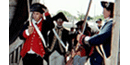 2 men in fine trimmed coats walk through a gate saluting with swords