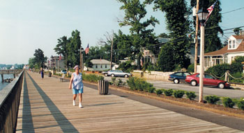 Woman walking on pedestrian boardwalk, water to left, road to the right