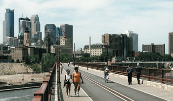 People walking on bridge with Minneapolis skyline in the background 