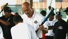 American Public Diplomacy Envoy Cal Ripken Jr. works with South African visitor Hilary Van den Heever on her batting technique as other memebers of the South African delegation look on.