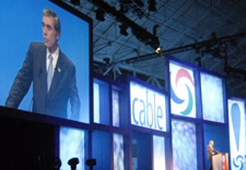 Gutierrez delivering remarks with large projected images in background. Click for larger image.