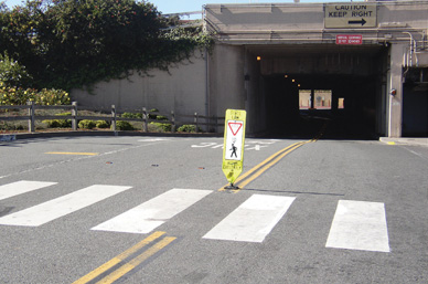 In-roadway knockdown signs, such as this one installed near the Golden Gate Bridge in San Francisco, are placed in the crosswalk as a highly visible reminder to motorists to yield to pedestrians in the crosswalk. Made from flexible materials, the signs bounce back up if knocked down by a vehicle.