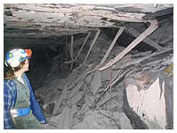 Miner examining the fallen roof inside a mine
