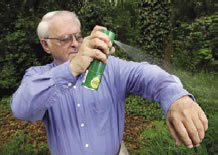 Photograph of man spraying mosquito repellant onto his clothing
