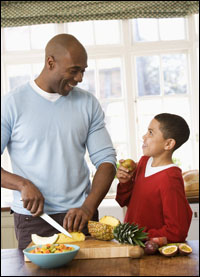Foto: un padre y un hijo preparando una ensalada de frutas