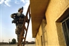 A U.S. soldier searches the roof of a building for evidence at a school complex in Narhwan, Iraq, May 9, 2008. The soldier is assigned to the 1st Armored Division's Battery C, 4th Battalion, 27th Field Artillery Regiment, 2nd Brigade Combat Team. 